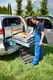 Aufnahme eines Mitarbeitenden für Hawido-Service der am geöffneten Heck eines Fahrzeuges steht und Schubladen mit Werkzeugen geöffnet hat.