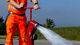 Aufnahme eines roten Hawle Hydranten, der zur Kontrolle gerade aufgedreht wird und Wasser spendet.
